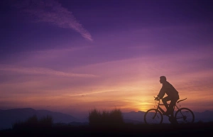 A man mountain biking at sunset on the Lake District hills, Cumbria, UK A man mountain biking at sunset on the Lake District hills, Cumbria, UK