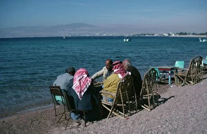 Images Dated 16th July 2008: JORDAN, Aqaba Group of men playing backgammon on shore of beach with Eliat