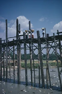 THAILAND Women carrying baskets on their heads crossing high wooden bridge across THAILAND Women carrying baskets on their heads crossing high wooden bridge across