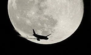 Images Dated 1st January 2010: An airplane is silhouetted against a full moon in the sky over London