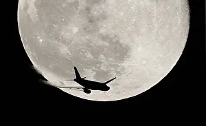 An airplane is silhouetted against a full moon in the sky over London An airplane is silhouetted against a full moon in the sky over London