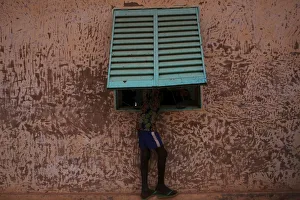 A boy peers through a window to watch electoral officials count ballots at a polling A boy peers through a window to watch electoral officials count ballots at a polling