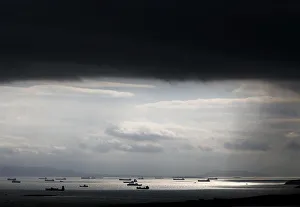 Cargo ships are seen sailing under storm clouds at open sea near the port of Piraeus Cargo ships are seen sailing under storm clouds at open sea near the port of Piraeus