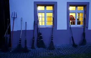A carnival reveller dressed as a witch (Kandelhexe) looks out of a window as a group of A carnival reveller dressed as a witch (Kandelhexe) looks out of a window as a group of