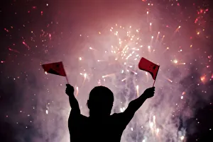 A Chinese girl waves national flags as she watches fireworks at the celebration of A Chinese girl waves national flags as she watches fireworks at the celebration of