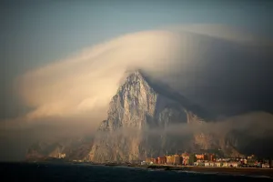 Prints of A cloud partially covers the tip of the Rock of the British territory of Gibraltar at sunrise from La Atunara port before Spanish fishermen sail in their fishing boats with their relatives to take Related Image Prints: Gibraltar Partially Covered by Cloud Print