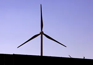 A construction worker walks on a new road located near a field of giant wind turbines A construction worker walks on a new road located near a field of giant wind turbines