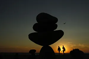 A couple walk past stone sculptures built on Moshup Beach as the sun sets in Aquinnah A couple walk past stone sculptures built on Moshup Beach as the sun sets in Aquinnah