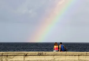 A couple watches a rainbow from Havanas seafront boulevard El Malecon A couple watches a rainbow from Havanas seafront boulevard El Malecon