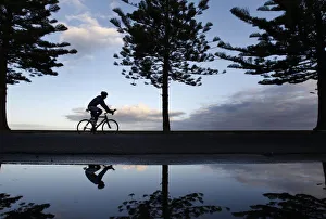 A cyclist is seen reflected while riding along a beach in Melbourne A cyclist is seen reflected while riding along a beach in Melbourne