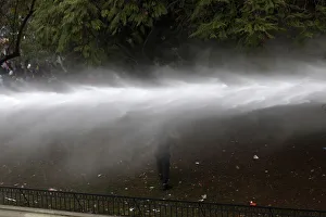 A demonstrator runs away from a jet of water during a 48-hour national strike at Santiago A demonstrator runs away from a jet of water during a 48-hour national strike at Santiago