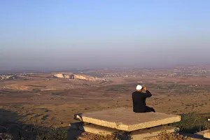 A Druze man uses binoculars as he looks towards Syria from part of an abandoned military A Druze man uses binoculars as he looks towards Syria from part of an abandoned military