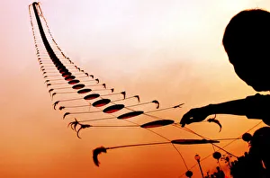 AN ELDERLY CHINESE MAN FLIES A KITE IN THE SHAPE OF A CENTIPEDE AT SUNSET IN WUHAN AN ELDERLY CHINESE MAN FLIES A KITE IN THE SHAPE OF A CENTIPEDE AT SUNSET IN WUHAN