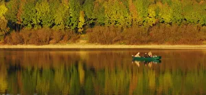FISHERMEN IN BOAT ARE CAMOUFLAGED BY COLOURS OF FALL AT DAM IN SLOVAKIA FISHERMEN IN BOAT ARE CAMOUFLAGED BY COLOURS OF FALL AT DAM IN SLOVAKIA