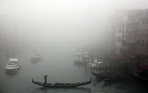 A gondolier rows his gondola across the Grand Canal in the fog in Venice A gondolier rows his gondola across the Grand Canal in the fog in Venice