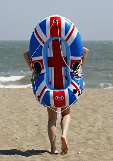 Holiday-maker walks towards the sea with her inflatable boat during heatwave in Skegness Holiday-maker walks towards the sea with her inflatable boat during heatwave in Skegness