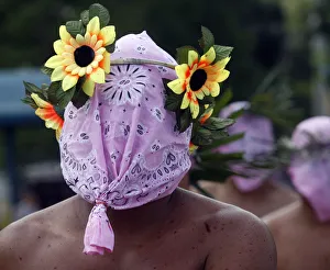 A hooded penitent wears an improvised crown made of plastic flowers during Maundy A hooded penitent wears an improvised crown made of plastic flowers during Maundy