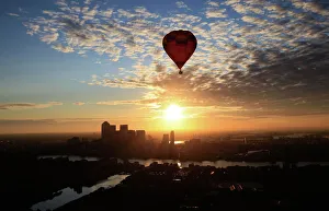 A hot air balloon rises into the early morning sky in front of the Canary Wharf financial A hot air balloon rises into the early morning sky in front of the Canary Wharf financial