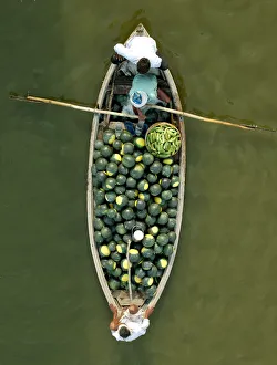 Indian farmers carry watermelons on a boat across the river Ganges in Allahabad Indian farmers carry watermelons on a boat across the river Ganges in Allahabad