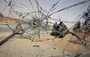 Libyan rebels manning a checkpoint near the front line are seen through a bullet-pocked Libyan rebels manning a checkpoint near the front line are seen through a bullet-pocked