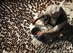 A man dries earthenware oil lamps or Diyo in the sun outside his workshop A man dries earthenware oil lamps or Diyo in the sun outside his workshop