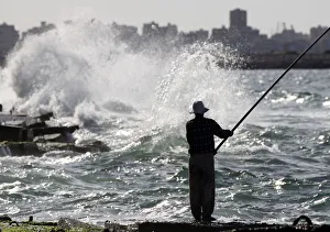 A man fishes along the shoreline in Alexandria A man fishes along the shoreline in Alexandria