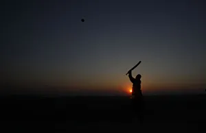 A man is silhouetted against the setting sun as he plays cricket at a park in Lahore A man is silhouetted against the setting sun as he plays cricket at a park in Lahore