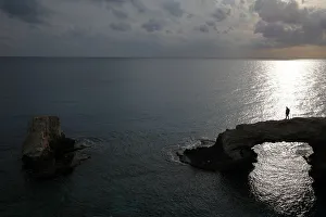A man walks on a natural rock arch in Ayia Napa A man walks on a natural rock arch in Ayia Napa