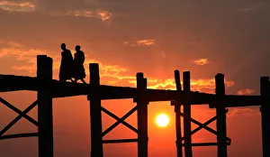 Monks walk along ancient teak bridge at Amarapura Monks walk along ancient teak bridge at Amarapura