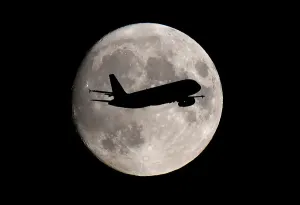 Prints of A passenger plane passes in front of the moon as it makes its final landing approach to Heathrow Airport in London, Britain September 12, 2019 Heathrow Airport Prints: Moonlit Plane Landing Print
