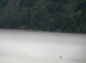 A motor boat sails through a low, fog-blanketed Yenisei River A motor boat sails through a low, fog-blanketed Yenisei River