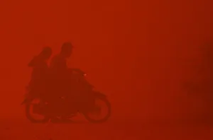 A motorcyclist turns back due to intense heat while passing through haze near burnt peat A motorcyclist turns back due to intense heat while passing through haze near burnt peat