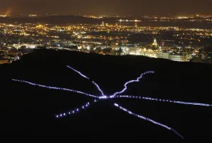 Print of runners in light suits on Arthurs Seat