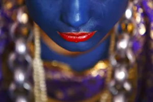 A Newari woman, with her lips and face painted to depic a deity, sits inside a house A Newari woman, with her lips and face painted to depic a deity, sits inside a house
