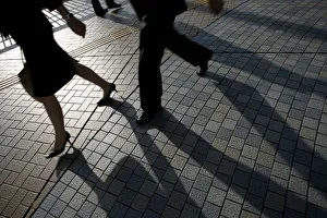 Pedestrians cast shadows as they walk on a street in Tokyo Pedestrians cast shadows as they walk on a street in Tokyo