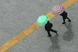 Pedestrians holding umbrellas walk on a street in the rain in central Seoul Pedestrians holding umbrellas walk on a street in the rain in central Seoul