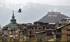 People cross a footbridge in front of cluster of traditional houses in Srinagar People cross a footbridge in front of cluster of traditional houses in Srinagar