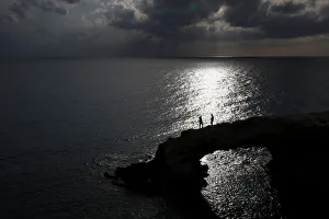 People walk on a natural rock arch in Ayia Napa People walk on a natural rock arch in Ayia Napa
