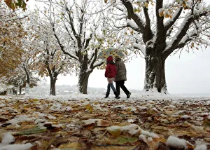 People walk through the snow and autumn leaves covered landscape in Herrsching People walk through the snow and autumn leaves covered landscape in Herrsching