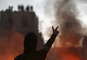 Protester opposing Egyptian President Mursi gestures at riot police during clashes in Protester opposing Egyptian President Mursi gestures at riot police during clashes in