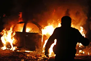 A protester runs after setting fire to a car during clashes with police in front of the A protester runs after setting fire to a car during clashes with police in front of the