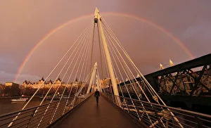A rainbow appears as a pedestrian crosses one of the Golden Jubilee Bridges in London A rainbow appears as a pedestrian crosses one of the Golden Jubilee Bridges in London