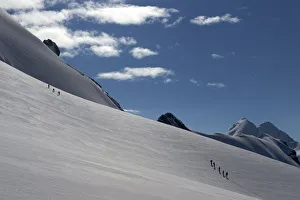 Roped parties of climbers walk on a glacier marking the border between Switzerland Roped parties of climbers walk on a glacier marking the border between Switzerland