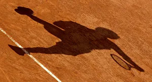THE SHADOW OF A TENNIS PLAYER AS HE SERVES IS CAST ON THE CLAY THE SHADOW OF A TENNIS PLAYER AS HE SERVES IS CAST ON THE CLAY
