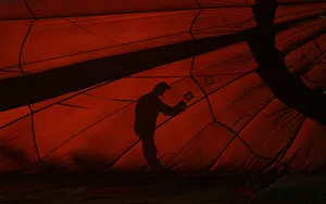 The silhouette of a handler is seen as he prepares a balloon for flight during the Hot The silhouette of a handler is seen as he prepares a balloon for flight during the Hot