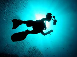 A silhouetted underwater photographer swims at a diving site near the island of Sipadan A silhouetted underwater photographer swims at a diving site near the island of Sipadan