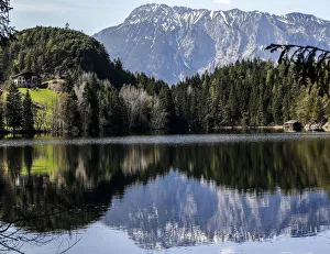 Snow covered mountains are reflected in Piburger lake on a sunny spring day in the Snow covered mountains are reflected in Piburger lake on a sunny spring day in the