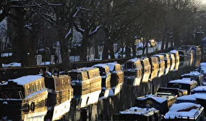 Snow is seen on top of narrow boats are seen at sunset on Regents Canal in Little Snow is seen on top of narrow boats are seen at sunset on Regents Canal in Little