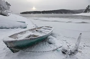 A Soviet-made plastic row boat covered in snow and hoarfrost lies on a snowy bank A Soviet-made plastic row boat covered in snow and hoarfrost lies on a snowy bank