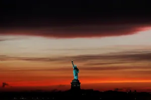 The sun sets behind the Statue of Liberty after a rain storm in New York The sun sets behind the Statue of Liberty after a rain storm in New York